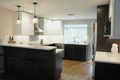 Mid-sized trendy medium tone wood floor eat-in kitchen photo in Seattle with an undermount sink, flat-panel cabinets, white cabinets, quartz countertops, white backsplash, ceramic backsplash, stainless steel appliances and a peninsula