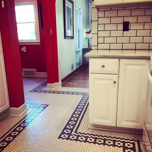 This is an example of a mid-sized eclectic galley separate kitchen in Kansas City with raised-panel cabinets, white cabinets, marble benchtops, white splashback, subway tile splashback, white appliances, porcelain floors, no island, yellow floor and white benchtop.