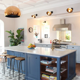 Design ideas for a traditional kitchen in Kent with a submerged sink, shaker cabinets, white cabinets, stainless steel appliances, medium hardwood flooring, an island, brown floors and white worktops.
