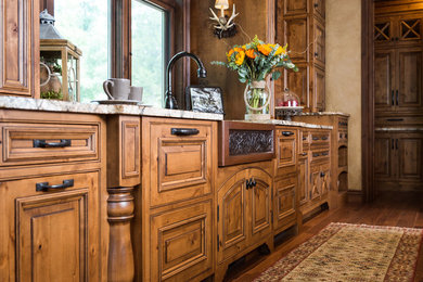Inspiration for a large rustic medium tone wood floor and brown floor kitchen remodel in St Louis with a farmhouse sink, raised-panel cabinets, dark wood cabinets, granite countertops, brown backsplash, stone tile backsplash, stainless steel appliances and two islands