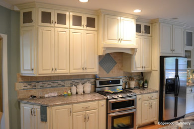 Kitchen - traditional medium tone wood floor kitchen idea in Raleigh with raised-panel cabinets, white cabinets, granite countertops, beige backsplash, ceramic backsplash and an island