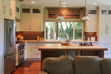Exempel på ett mellanstort klassiskt kök, med en undermonterad diskho, skåp i shakerstil, vita skåp, granitbänkskiva, grått stänkskydd, stänkskydd i tunnelbanekakel, rostfria vitvaror, mellanmörkt trägolv och en köksö