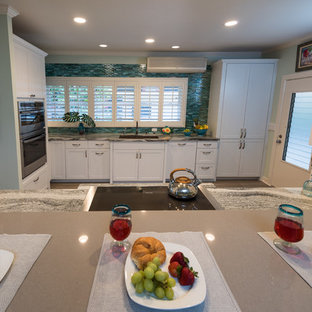 Photo of a mid-sized tropical separate kitchen in Hawaii with an undermount sink, shaker cabinets, white cabinets, quartzite benchtops, blue splashback, glass tile splashback, panelled appliances, vinyl floors, no island and grey floor.