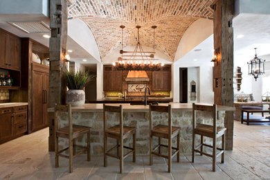 Inspiration for a mediterranean kitchen in Houston with dark wood cabinets, integrated appliances and an island.