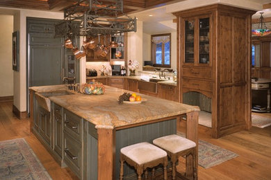 Example of a large cottage u-shaped medium tone wood floor eat-in kitchen design in Denver with a farmhouse sink, raised-panel cabinets, distressed cabinets, granite countertops, multicolored backsplash, paneled appliances and an island