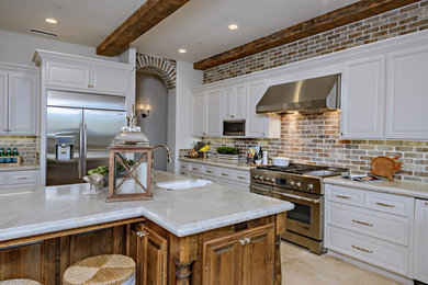 Inspiration for a large country u-shaped travertine floor and beige floor enclosed kitchen remodel in Other with a farmhouse sink, raised-panel cabinets, beige cabinets, quartzite countertops, brown backsplash, brick backsplash, stainless steel appliances and an island