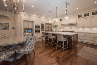 Example of a large tuscan medium tone wood floor eat-in kitchen design in Vancouver with beaded inset cabinets, beige cabinets, quartz countertops, white backsplash, stone tile backsplash, stainless steel appliances and an island