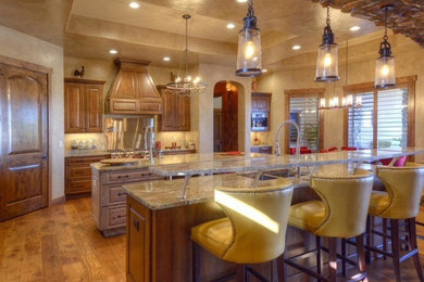 Example of a tuscan medium tone wood floor kitchen design in Denver with an undermount sink, raised-panel cabinets, medium tone wood cabinets, granite countertops, stainless steel appliances and two islands