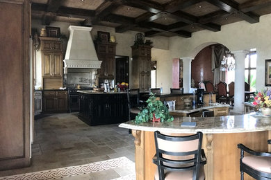 Mountain style limestone floor kitchen photo in Phoenix with an undermount sink, raised-panel cabinets, brown cabinets, granite countertops, paneled appliances and two islands