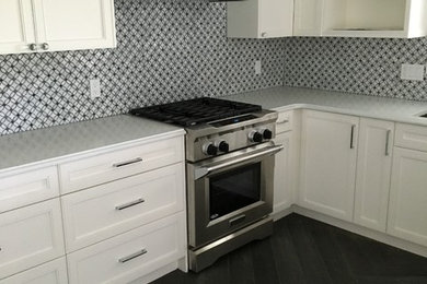 Example of a large transitional porcelain tile kitchen design in Calgary with raised-panel cabinets, white cabinets, quartzite countertops, gray backsplash, mosaic tile backsplash and stainless steel appliances