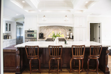 Transitional dark wood floor kitchen photo in Orange County with raised-panel cabinets, white cabinets, marble countertops, stainless steel appliances and an island
