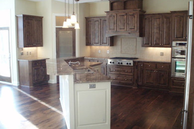 Photo of a medium sized classic l-shaped open plan kitchen in Minneapolis with a double-bowl sink, raised-panel cabinets, dark wood cabinets, beige splashback, ceramic splashback, stainless steel appliances, dark hardwood flooring and an island.