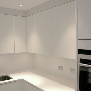 Small contemporary u-shaped separate kitchen in London with a drop-in sink, white cabinets, solid surface benchtops, white splashback, stainless steel appliances and yellow benchtop.