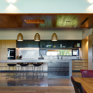 Design ideas for a contemporary galley open plan kitchen in Sunshine Coast with flat-panel cabinets, medium wood cabinets, black appliances, concrete floors, with island, brown floor, grey benchtop and wood.