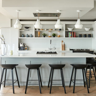 Medium sized contemporary galley kitchen in Other with blue cabinets, quartz worktops, an island, white worktops, a submerged sink, shaker cabinets, white splashback, integrated appliances, medium hardwood flooring and beige floors.
