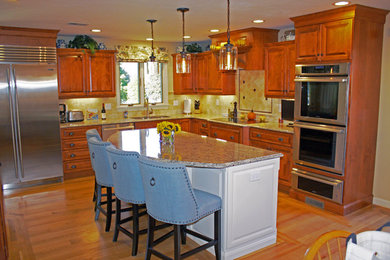 Eat-in kitchen - large transitional u-shaped light wood floor eat-in kitchen idea in Boston with an undermount sink, raised-panel cabinets, medium tone wood cabinets, granite countertops, beige backsplash, stone tile backsplash, stainless steel appliances and an island