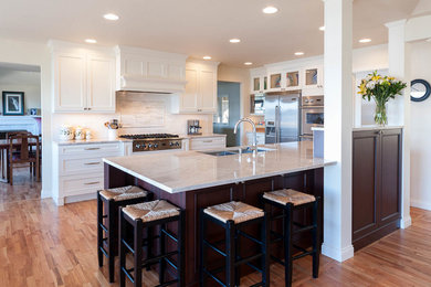 Eat-in kitchen - large craftsman l-shaped light wood floor eat-in kitchen idea in Seattle with an undermount sink, shaker cabinets, white cabinets, quartz countertops, white backsplash, subway tile backsplash, stainless steel appliances and an island