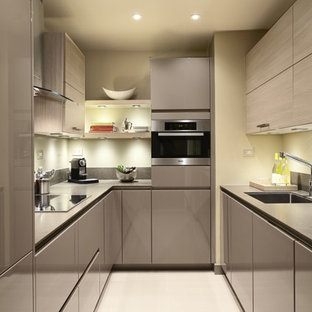 Enclosed kitchen - small modern u-shaped beige floor enclosed kitchen idea in New York with flat-panel cabinets, light wood cabinets, gray backsplash, stainless steel appliances, no island and gray countertops