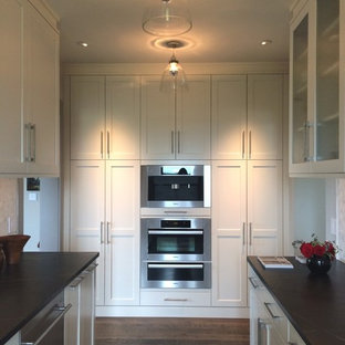 Inspiration pour une très grand arrière-cuisine parallèle design avec un évier encastré, un placard avec porte à panneau encastré, des portes de placard blanches, un plan de travail en stéatite, une crédence blanche, une crédence en carrelage de pierre, un électroménager en acier inoxydable, un sol en bois foncé et aucun îlot.