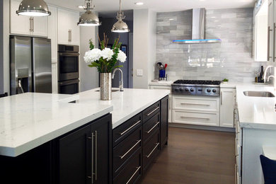 Example of a large transitional l-shaped brown floor, vinyl floor and shiplap ceiling kitchen pantry design in New York with shaker cabinets, black cabinets, gray backsplash, marble backsplash, stainless steel appliances, a drop-in sink, marble countertops, an island and white countertops