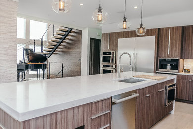 Example of a large trendy light wood floor open concept kitchen design in Boston with an undermount sink, flat-panel cabinets, brown cabinets, quartzite countertops, white backsplash, glass tile backsplash, stainless steel appliances and an island