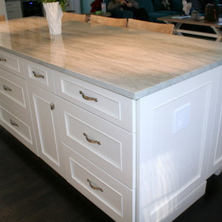 This is an example of a mid-sized shabby-chic style l-shaped open plan kitchen in Boston with a farmhouse sink, recessed-panel cabinets, white cabinets, granite benchtops, green splashback, glass tile splashback, stainless steel appliances, dark hardwood floors and with island.