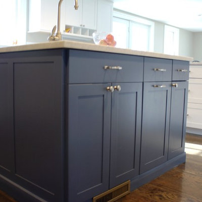 Open concept kitchen - mid-sized traditional l-shaped dark wood floor open concept kitchen idea in Boston with a farmhouse sink, recessed-panel cabinets, white cabinets, marble countertops, paneled appliances and an island