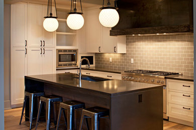 Eat-in kitchen - mid-sized traditional light wood floor eat-in kitchen idea in Calgary with an undermount sink, white cabinets, gray backsplash, subway tile backsplash, paneled appliances, an island, shaker cabinets and concrete countertops