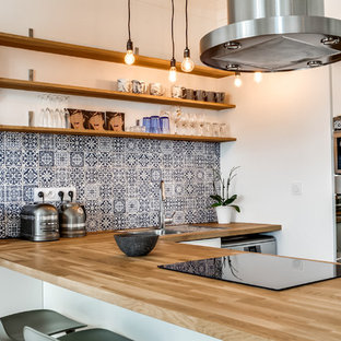 Idée de décoration pour une cuisine ouverte design en U avec un évier posé, un placard sans porte, un plan de travail en bois, une crédence multicolore, une crédence en carreau de ciment, un électroménager en acier inoxydable et une péninsule.