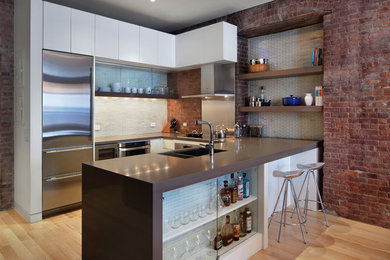 Example of a trendy u-shaped medium tone wood floor open concept kitchen design in New York with a double-bowl sink, flat-panel cabinets, white cabinets, stainless steel appliances and a peninsula