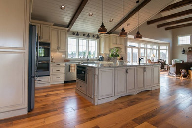 Inspiration for an expansive traditional u-shaped open plan kitchen in Boston with a belfast sink, raised-panel cabinets, beige cabinets, granite worktops, stainless steel appliances, medium hardwood flooring and an island.