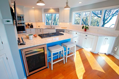 Kitchen photo in Portland Maine with quartz countertops, white backsplash and stainless steel appliances