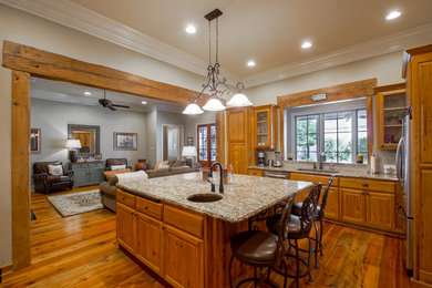 Enclosed kitchen - mid-sized traditional u-shaped medium tone wood floor enclosed kitchen idea in New Orleans with an undermount sink, raised-panel cabinets, medium tone wood cabinets, granite countertops, stainless steel appliances and an island