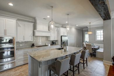 Inspiration for a mid-sized transitional l-shaped porcelain tile open concept kitchen remodel in New Orleans with an undermount sink, recessed-panel cabinets, gray cabinets, granite countertops, gray backsplash, glass tile backsplash, stainless steel appliances and an island