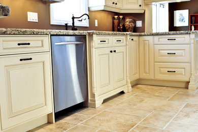 Modelo de cocina clásica con armarios con paneles con relieve, puertas de armario blancas, encimera de granito y suelo de piedra caliza