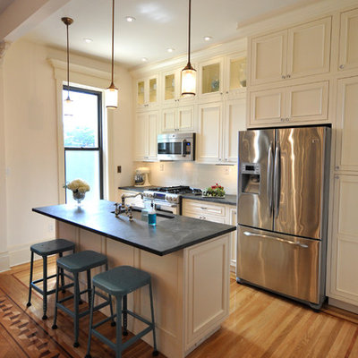 Kitchen - traditional galley kitchen idea in New York with recessed-panel cabinets, stainless steel appliances, an undermount sink, beige cabinets and soapstone countertops