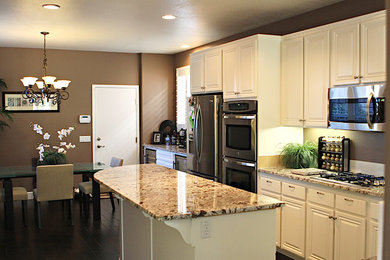 Mid-sized elegant l-shaped dark wood floor eat-in kitchen photo in San Diego with raised-panel cabinets, white cabinets, granite countertops, brown backsplash, stainless steel appliances and an island