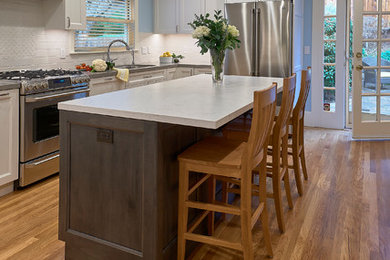 Enclosed kitchen - mid-sized transitional u-shaped medium tone wood floor and brown floor enclosed kitchen idea in San Francisco with an undermount sink, shaker cabinets, gray cabinets, quartz countertops, white backsplash, ceramic backsplash, stainless steel appliances and an island