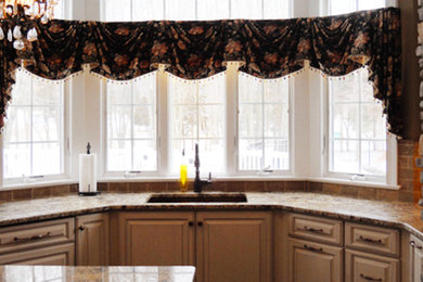 Example of a mid-sized u-shaped kitchen design in New York with an undermount sink, recessed-panel cabinets, beige cabinets, granite countertops, brown backsplash, stone slab backsplash and an island