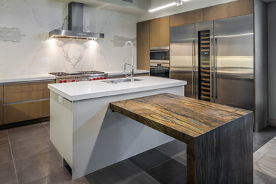 Example of a mid-sized trendy u-shaped porcelain tile and gray floor open concept kitchen design in Phoenix with an undermount sink, flat-panel cabinets, light wood cabinets, quartzite countertops, white backsplash, porcelain backsplash, stainless steel appliances, an island and white countertops