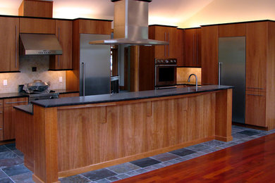 Exemple d'une grande cuisine américaine tendance en U et bois brun avec un évier encastré, un placard à porte plane, un électroménager en acier inoxydable, îlot, une crédence beige, un sol en ardoise et un sol gris.