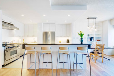 Example of a small trendy l-shaped porcelain tile and gray floor open concept kitchen design in New York with a single-bowl sink, flat-panel cabinets, white cabinets, quartz countertops, white backsplash, subway tile backsplash, stainless steel appliances, an island and gray countertops