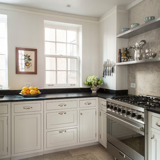 Diseño de cocina en U, tradicional, pequeña, con fregadero bajoencimera, armarios estilo shaker, puertas de armario beige, encimera de esteatita, salpicadero beige, salpicadero de piedra caliza, electrodomésticos de acero inoxidable, suelo de piedra caliza, suelo beige y encimeras negras
