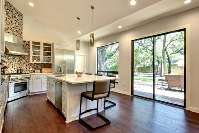 This is an example of a medium sized contemporary u-shaped open plan kitchen in Austin with a submerged sink, shaker cabinets, engineered stone countertops, mosaic tiled splashback, stainless steel appliances, dark hardwood flooring, an island, white cabinets and multi-coloured splashback.
