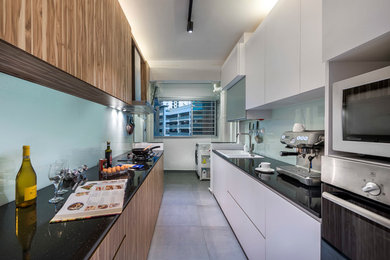 シンガポールにある中くらいなインダストリアルスタイルのおしゃれなキッチン (ダブルシンク、フラットパネル扉のキャビネット、中間色木目調キャビネット、御影石カウンター、白いキッチンパネル、ガラス板のキッチンパネル、シルバーの調理設備、セラミックタイルの床、アイランドなし) の写真