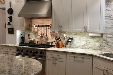 Large classic galley enclosed kitchen in New York with a submerged sink, shaker cabinets, white cabinets, granite worktops, multi-coloured splashback, mosaic tiled splashback, stainless steel appliances and cork flooring.