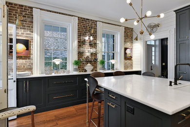 Eat-in kitchen - large contemporary u-shaped dark wood floor and brown floor eat-in kitchen idea in Charleston with recessed-panel cabinets, black cabinets, marble countertops, an island, white countertops, white backsplash, mosaic tile backsplash, a farmhouse sink and paneled appliances