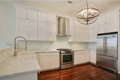 Photo of a modern kitchen/diner in New Orleans with a submerged sink, shaker cabinets, white cabinets, marble worktops, white splashback, stainless steel appliances and medium hardwood flooring.