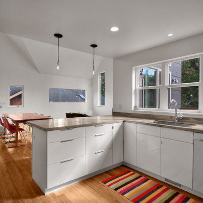 Minimalist eat-in kitchen photo in Seattle with white appliances, a single-bowl sink, flat-panel cabinets and white cabinets