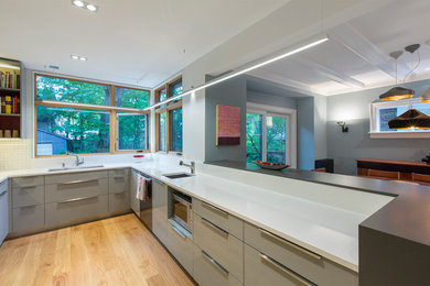 Eat-in kitchen - mid-sized contemporary u-shaped light wood floor eat-in kitchen idea in Toronto with an undermount sink, flat-panel cabinets, gray cabinets, quartz countertops, white backsplash, porcelain backsplash, stainless steel appliances and a peninsula